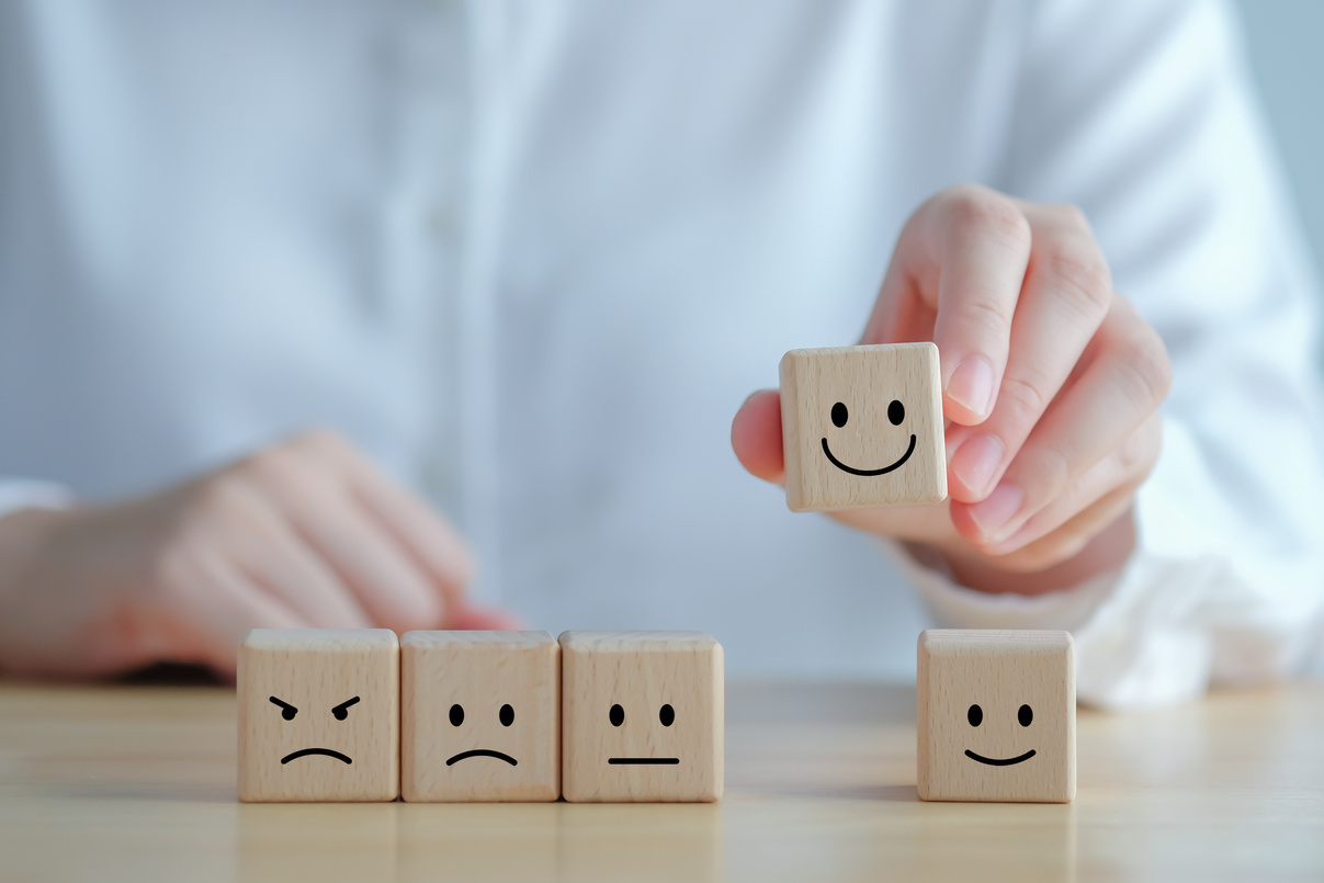 a person holding wooden blocks with a variety of smiley faces on them