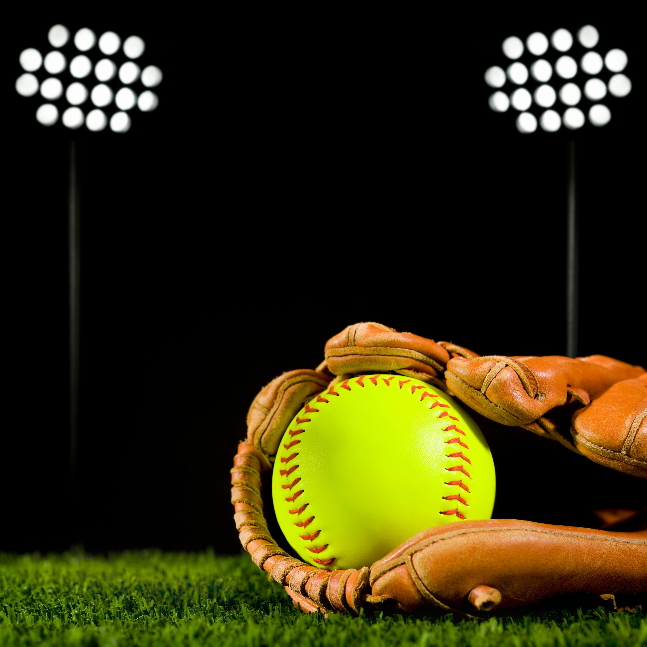 a softball in a glove on a green field